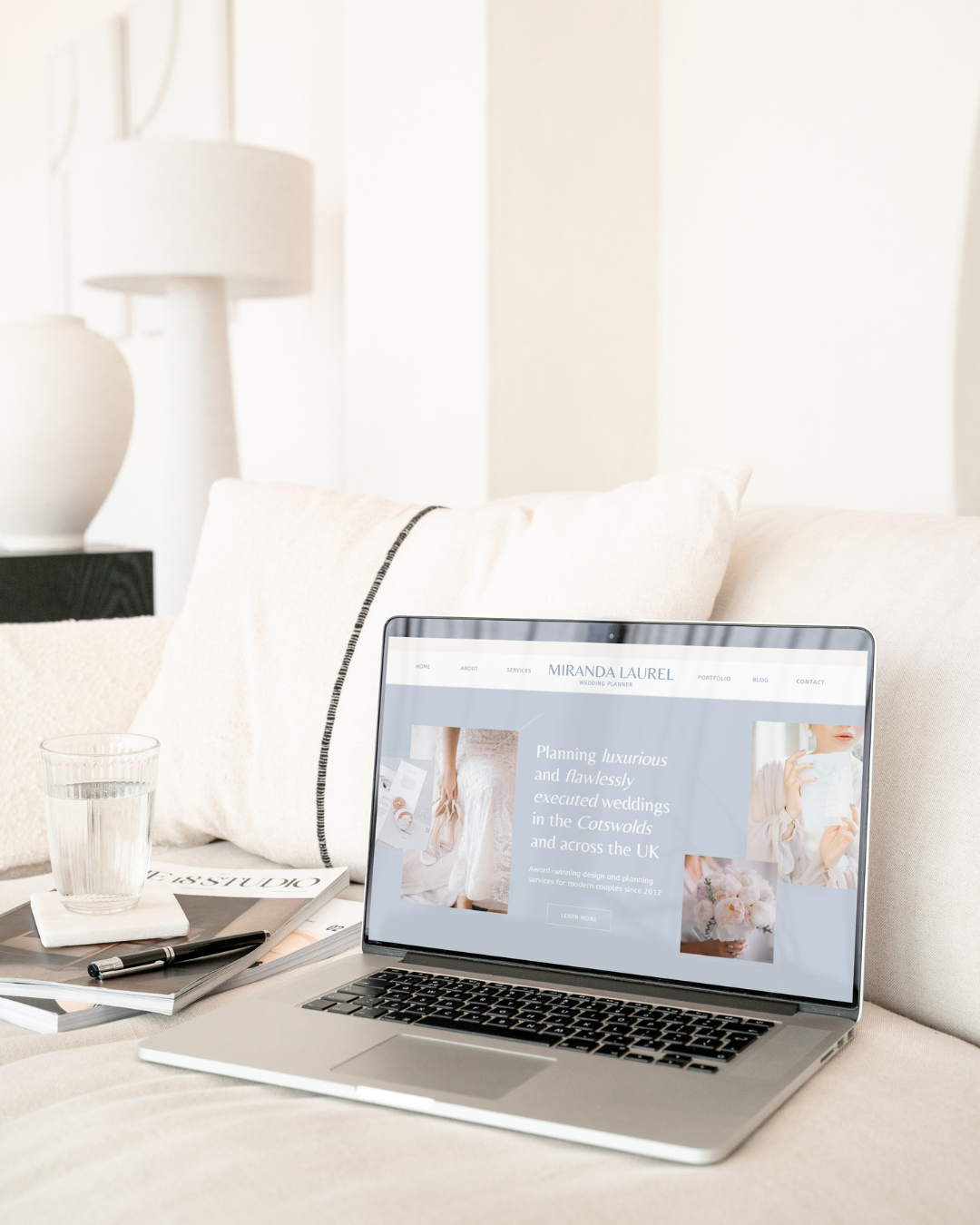 A laptop on a cream sofa, showing a website for wedding planners on the screen.