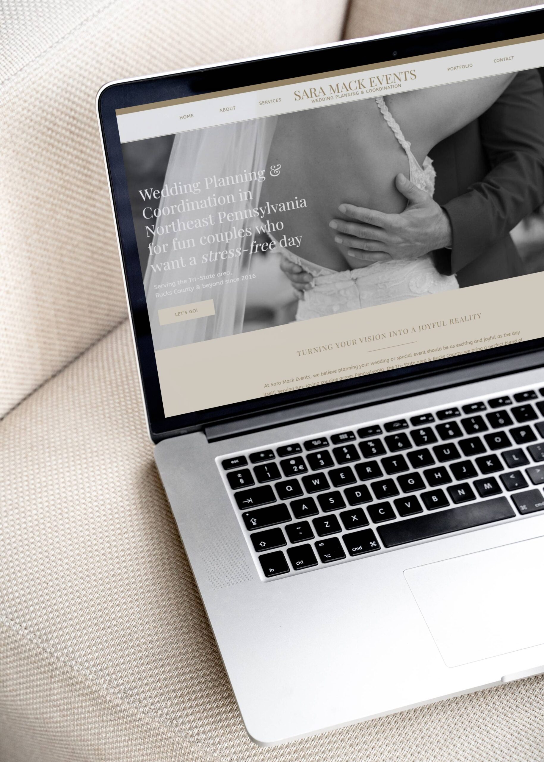 A laptop on a beige sofa, with a wedding business website homepage on the screen showing a Pennsylvania wedding planners website, with a photo of a bride & groom.