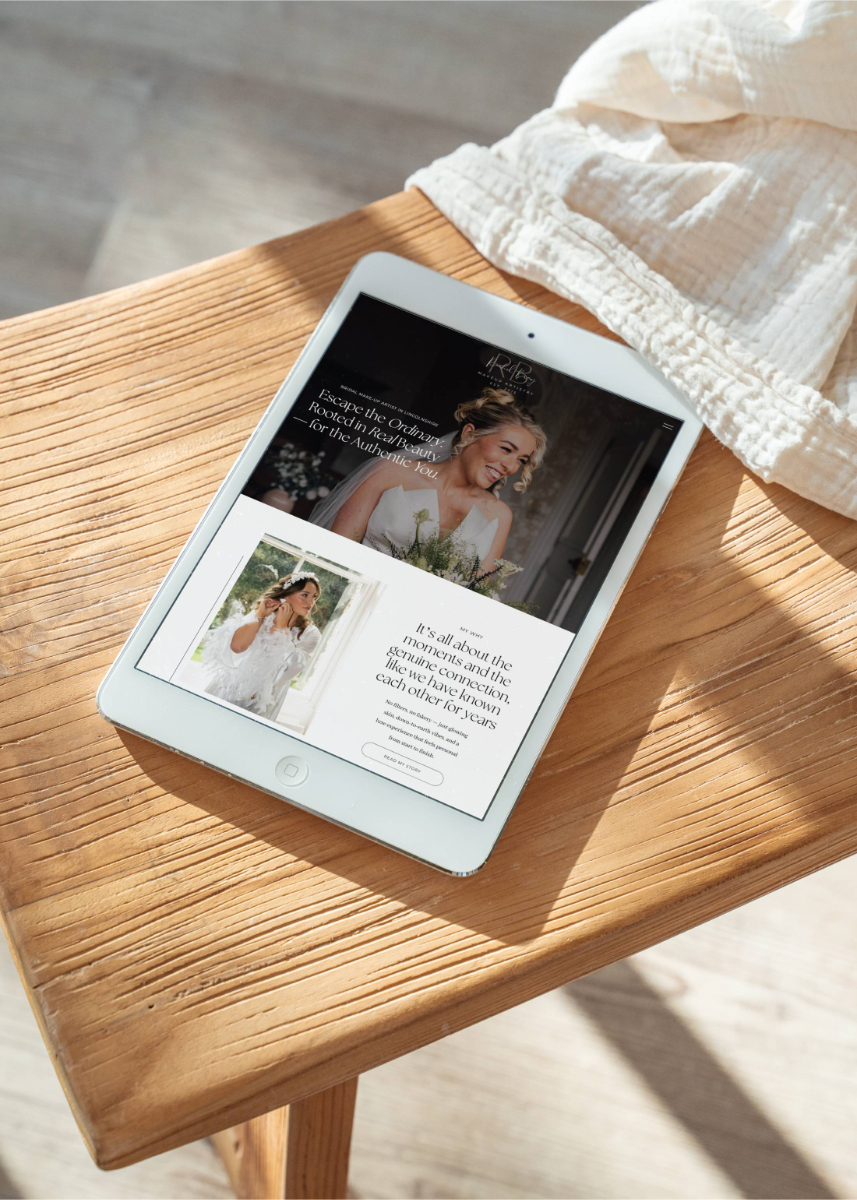 An image of an ipad on a wooden stool, with the screen showing Rachel Bray Makeup Artistry homepage website.